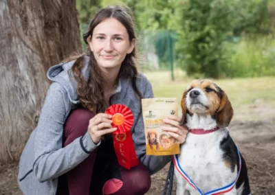 chien avec une femme montrant la médaille gagnée au challenge sportif du 12 mai 2023